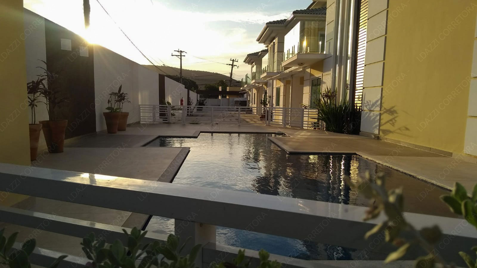 Piscina ao pôr do sol refletindo as fachadas do Condomínio Aurum Pescatore