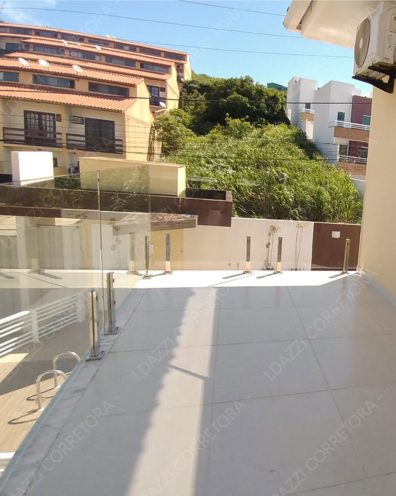 Varanda com guarda-corpo em vidro estruturado e piso em tom claro